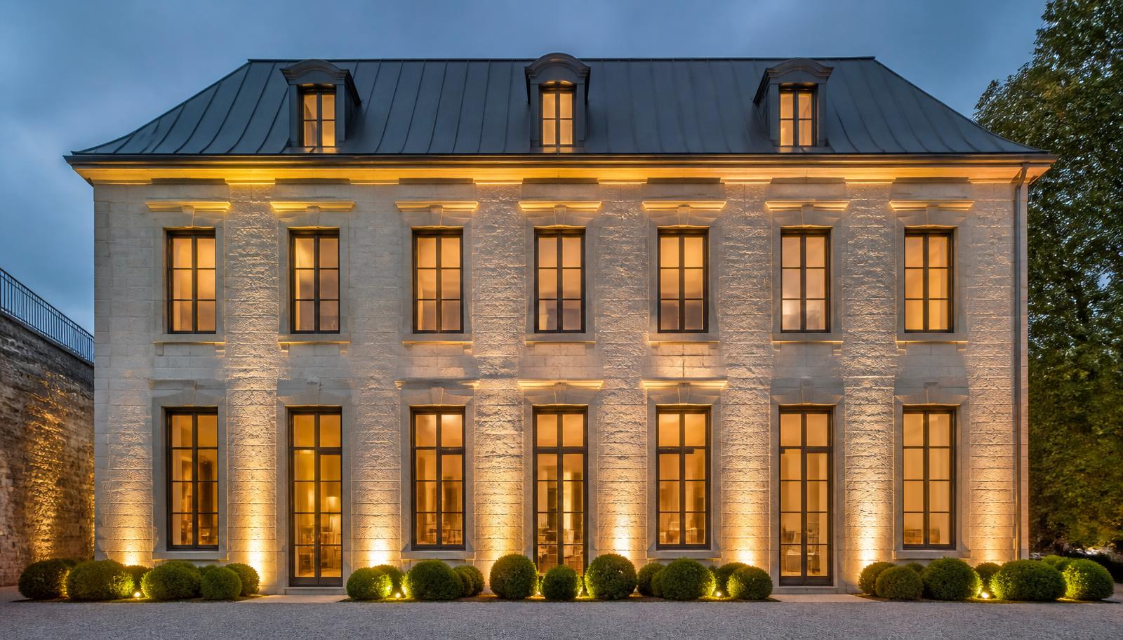 Le bâtiment après rénovation, façade en pierre claire restaurée et éclairée